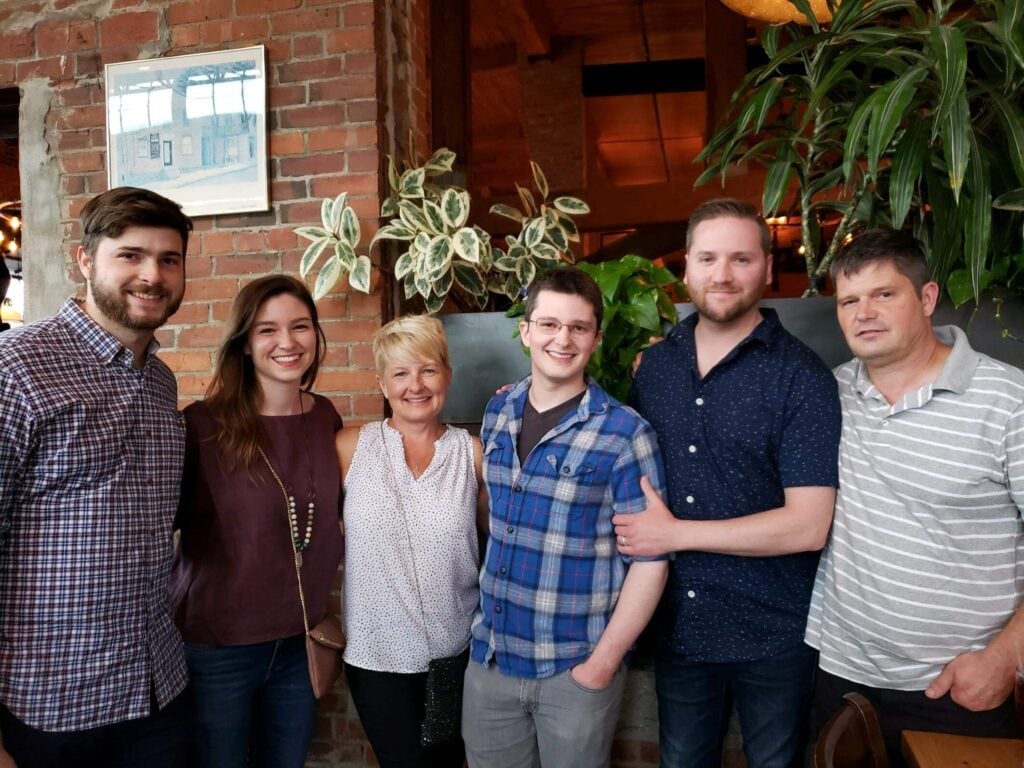 Sam smiling with family at a restaurant