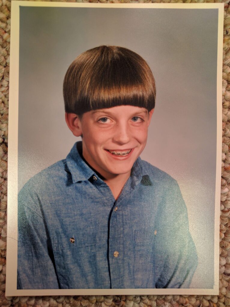 Smiling school-aged child with braces and a bowl cut hairstyle