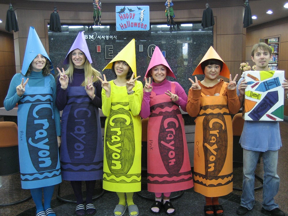 a group of people dressed up as crayons next to a crayon box