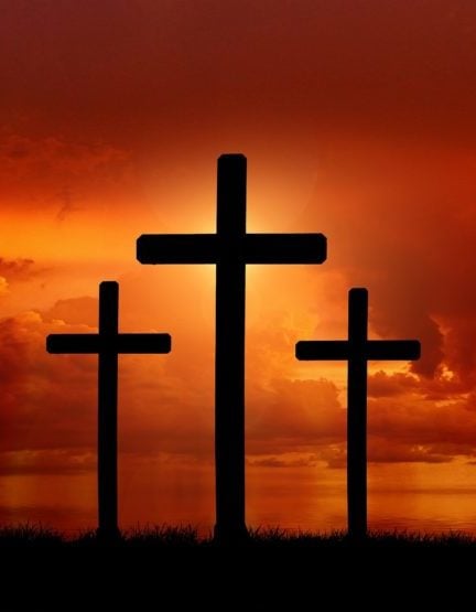 three crosses in front of a red/yellow sunset