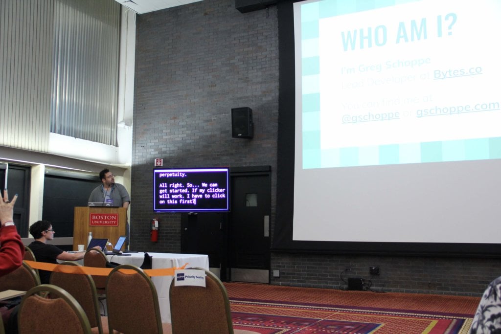 Photo of Greg Schoppe at a speakers podium, preparing to give his presentation