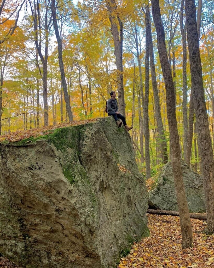 Chris on top of a large boulder in fall foliage