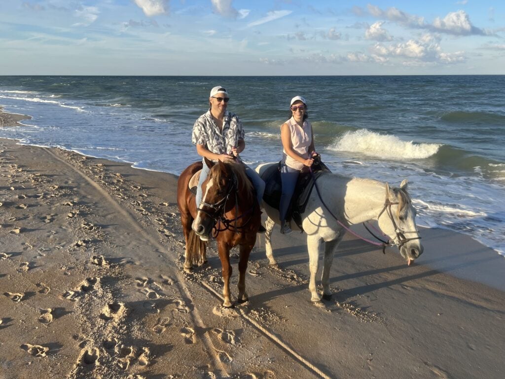 Randy and his wife on horseback by the beach