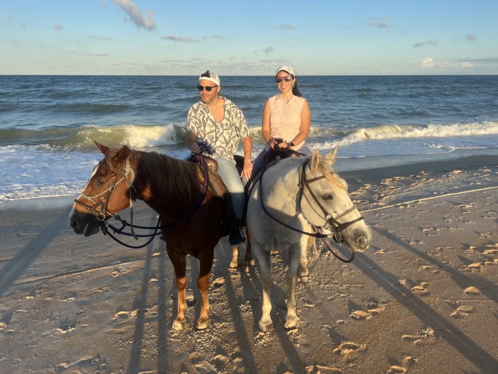 Randy and his wife on horseback by the beach