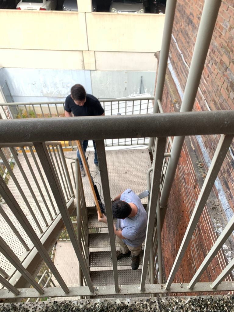 two Bytes employees moving their desks down the fire escape and into the second floor