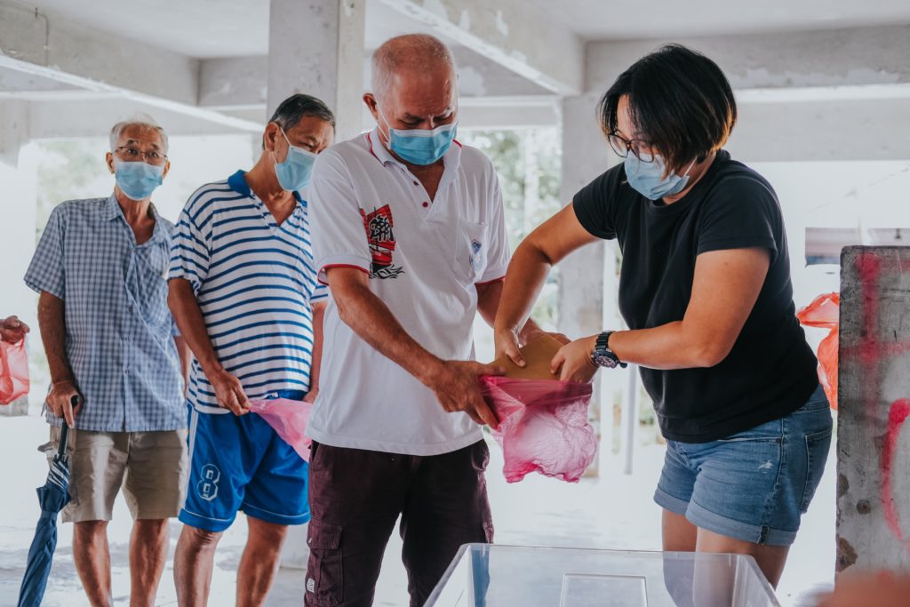 image of people in masks putting something in a pink plastic bag