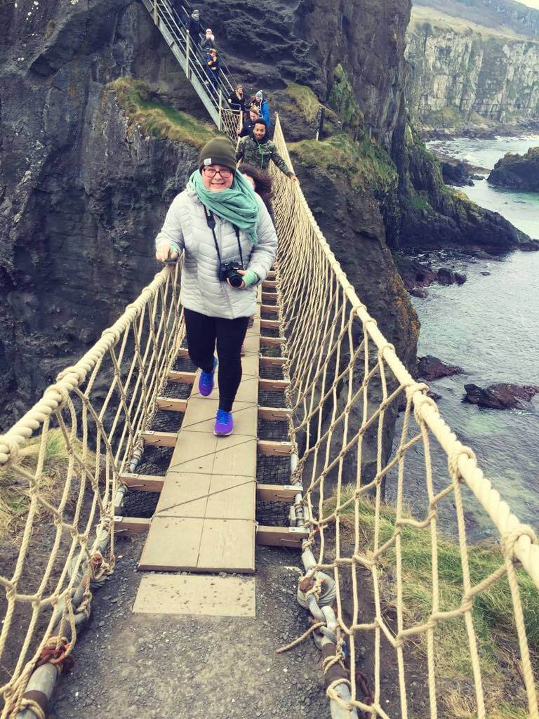 Hannah walking on a rope bridge across a cliff