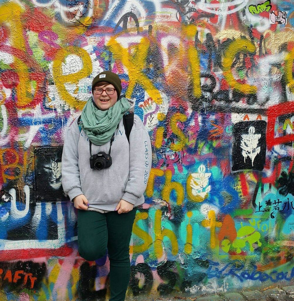 Hannah posing in front of a colorfully painted wall