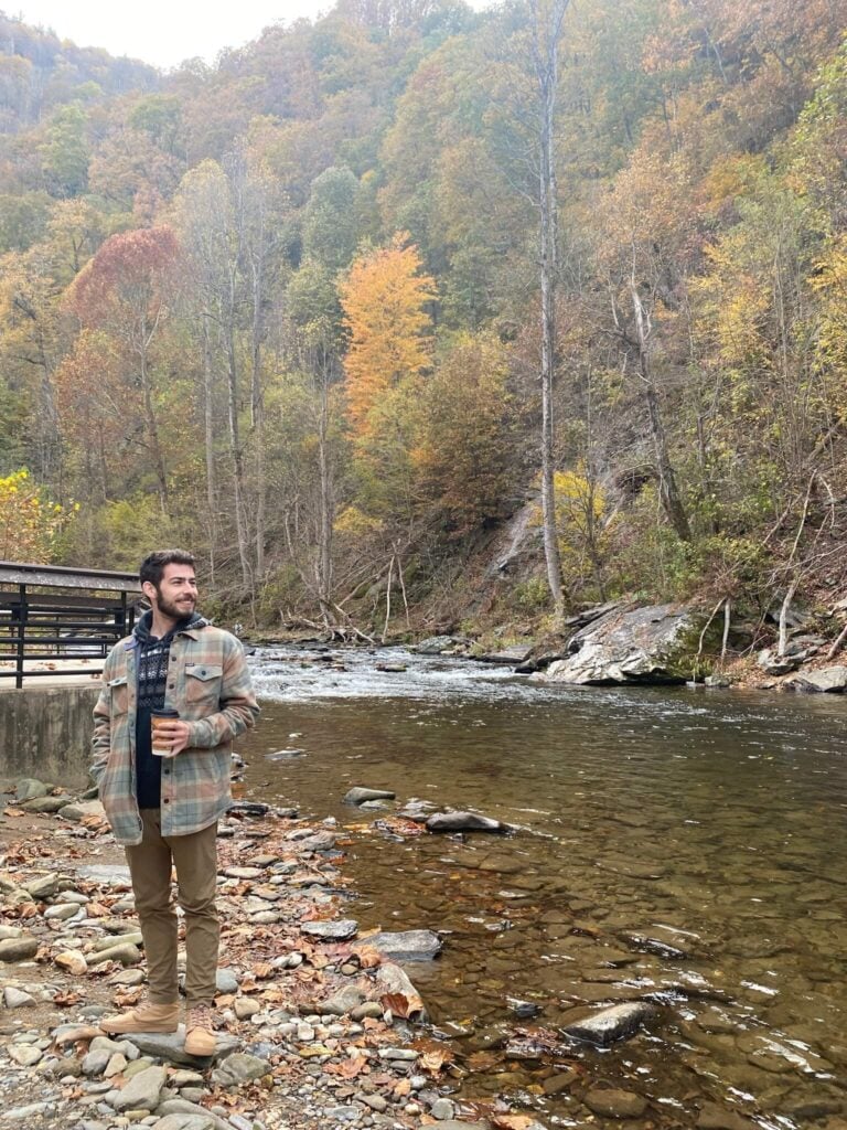 Tyler by a brook in the midst of some fall foliage