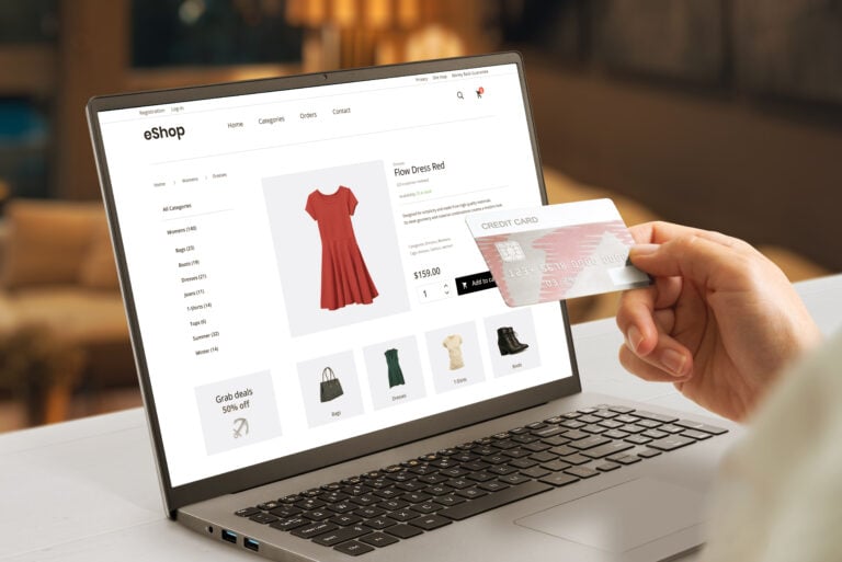 Woman holding credit card and looking at product details for a dress on a laptop