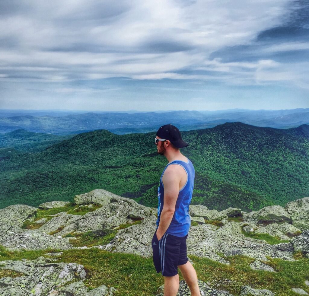 Portrait of Josh looking out across a green mountain peak