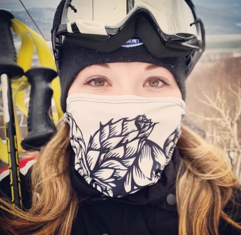 Emily posing with a ski mask, helmet and goggles on the mountain