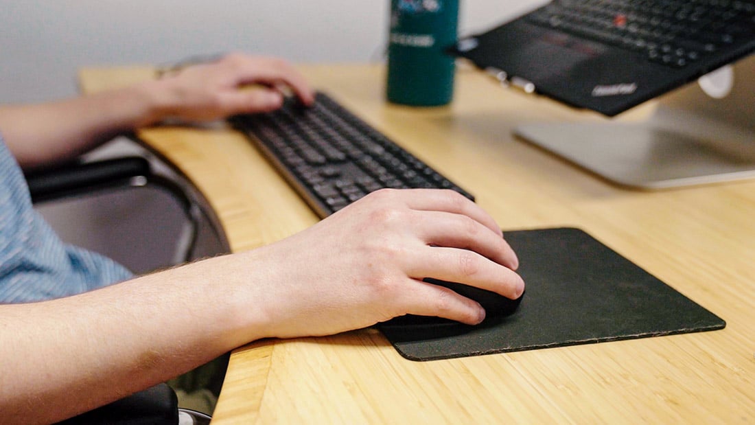 Close up of a developer's hands using a keyboard and mouse as he works on making a website accessible.