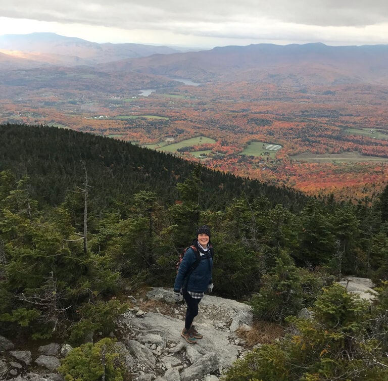 Kristina stands at the top of Mount Hunger in Vermont during a cloudy day in autumn