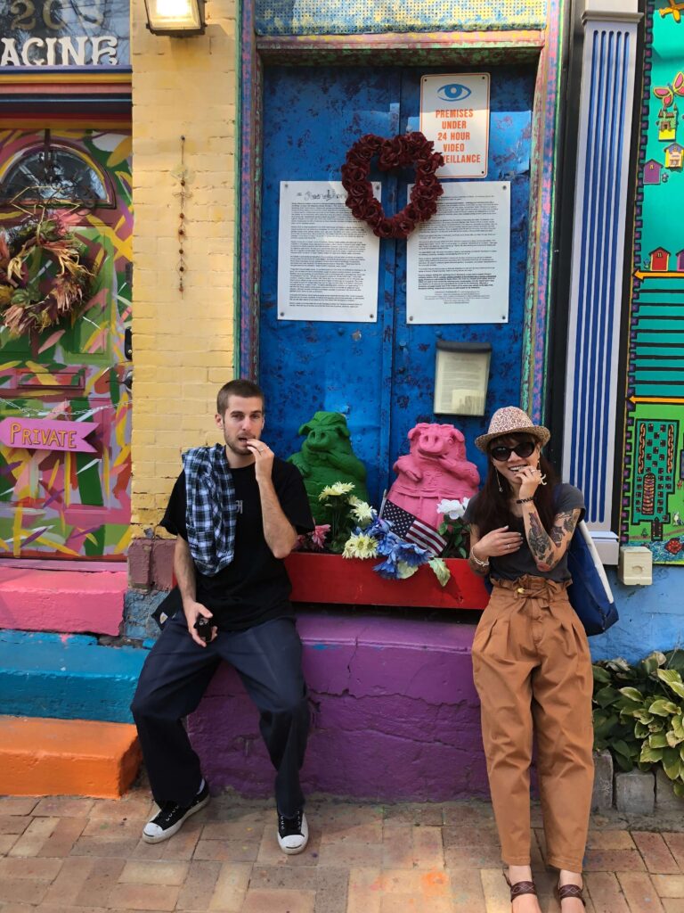 a man and a woman next to two statues of pigs, mimicking the pig's poses