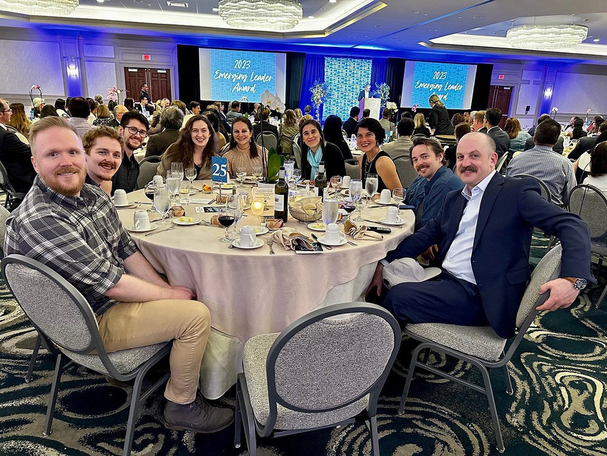 Nine smiling people sitting at a banquet table while attending the Lake Champlain Regional Chamber of Commerce Annual Dinner.
