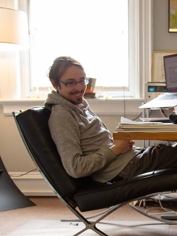 Jay, Bytes.co CEO, is leaning back in his chair at his desk, smiling at someone off camera; office setting, warmly lit by a large window behind him