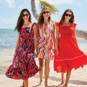 Three women standing on a beach together wearing Jude Connally dresses