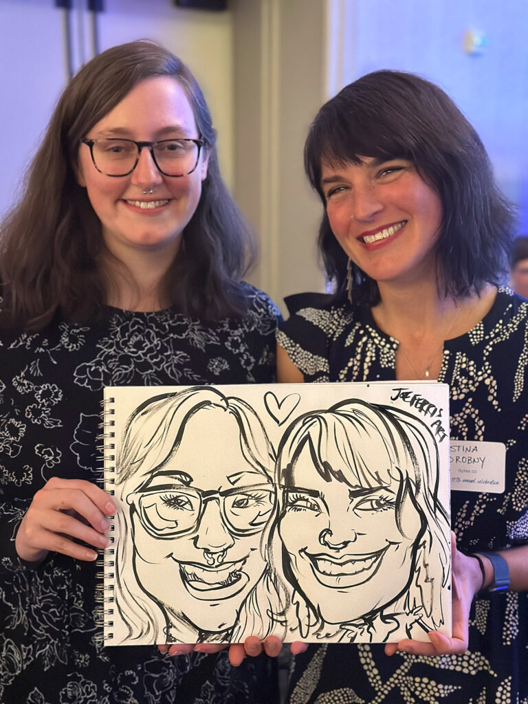 Lilly and Kristina hold up their caricature drawn by Joe Ferris Art at the Lake Champlain Chamber's 113th Annual Dinner