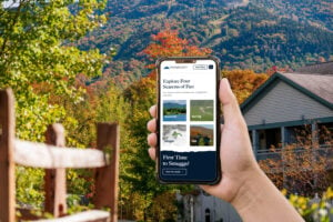 A hand holding an iPhone with the Smugglers' Notch Resort homepage on the screen