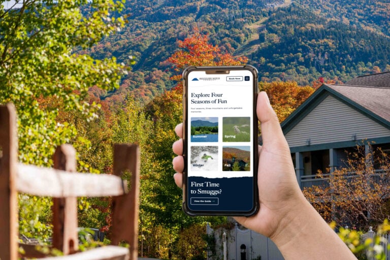 A hand holding an iPhone with the Smugglers' Notch Resort homepage on the screen