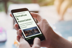 Someone holding an iPhone with a Donahue & Associates Google retargeting ad on the screen