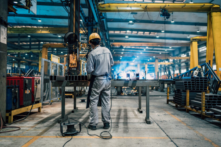 A man in a hardhat working in a manufacturing facility